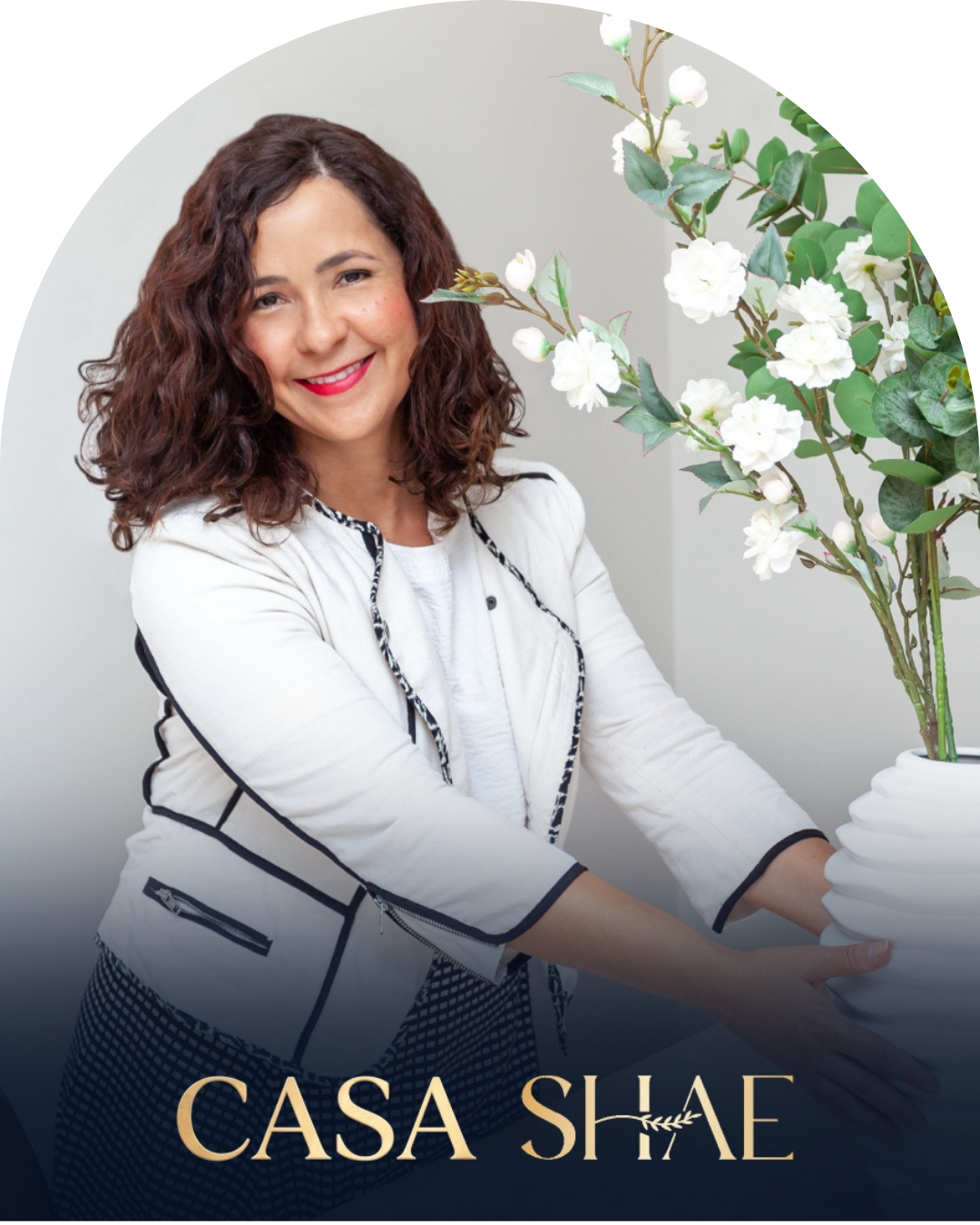 Retrato de Shae Campos ao lado de flores brancas, com a assinatura Casa Shae